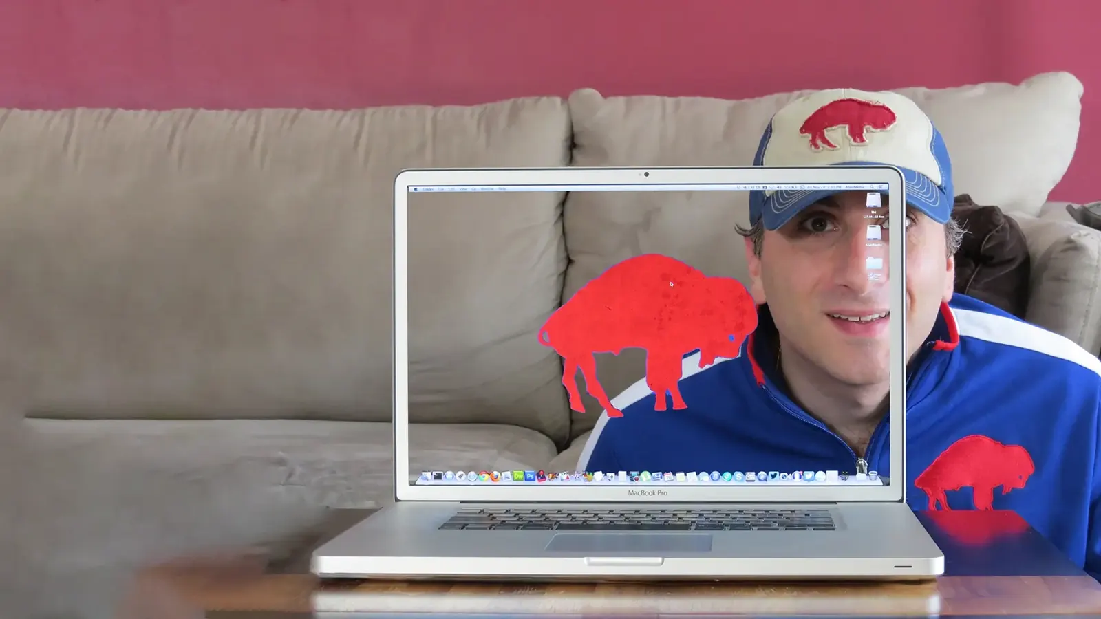 Aldo in a Buffalo Bills cap behind a see-through MacBook Pro